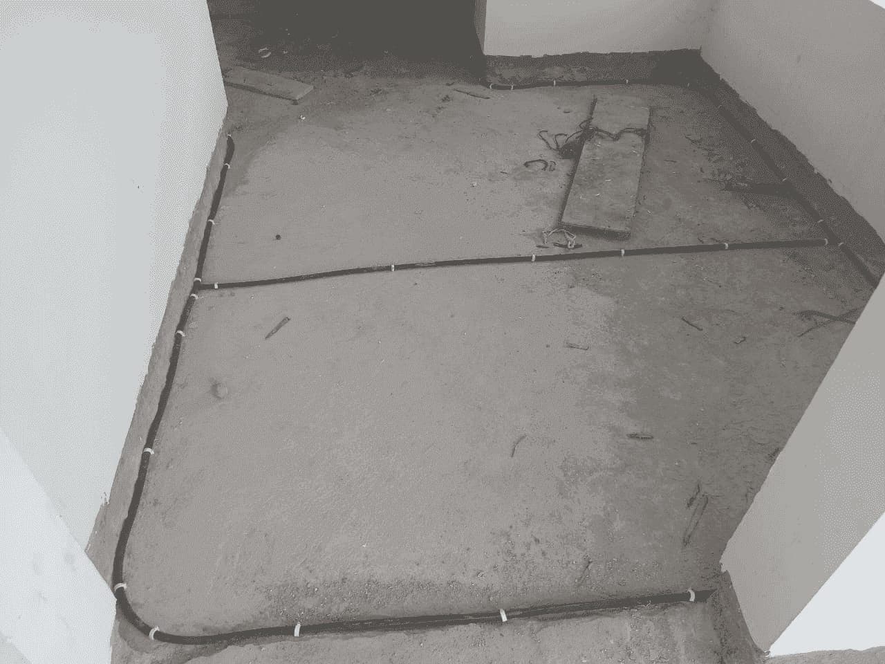 Anti-termite pipe clipped along the joint between wall and floor in an unfinished room