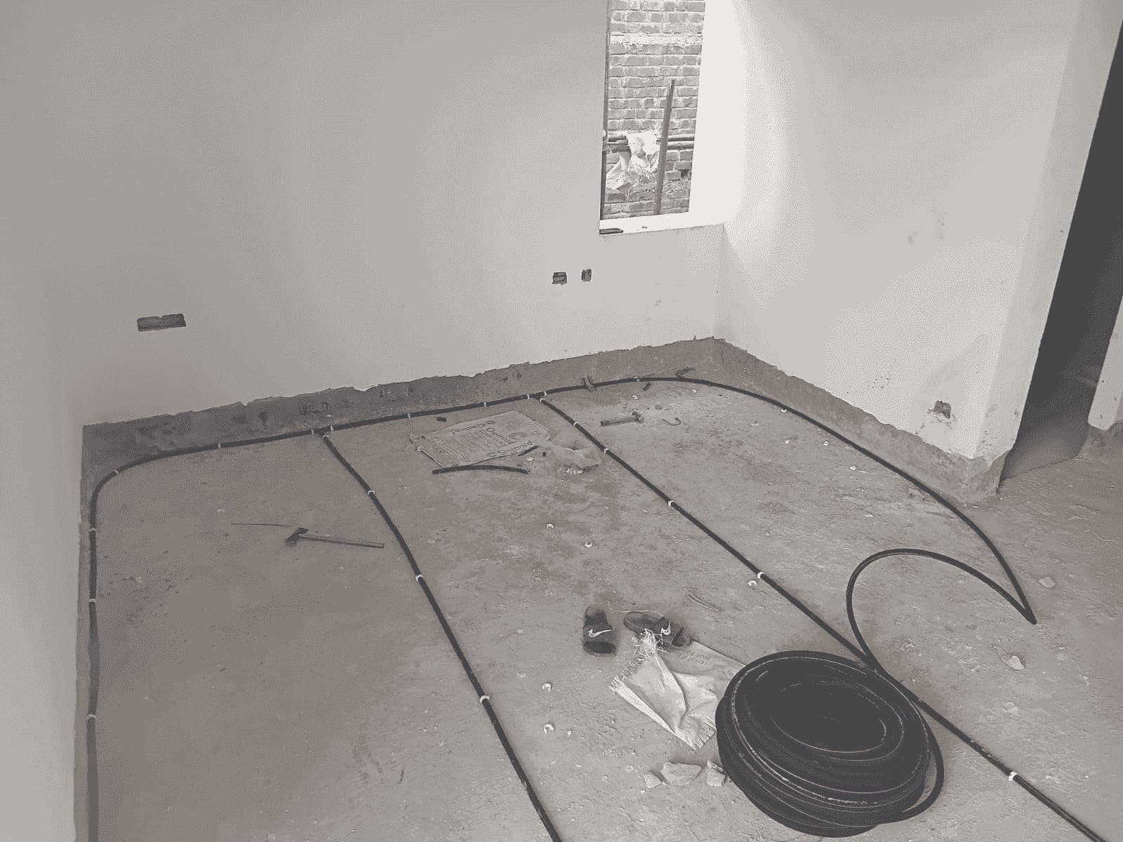 A coil of anti-termite pipe next to pipe lines being laid out on a concrete floor